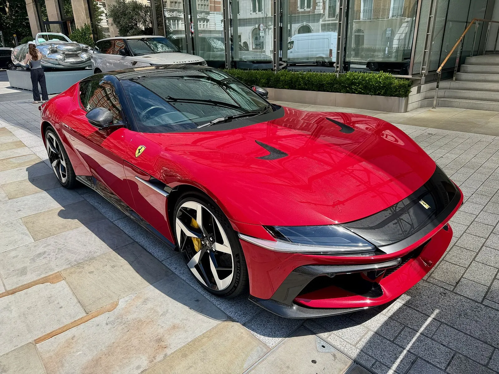 Red Ferrari 12Cilindri parked on a city plaza, front three-quarter view
